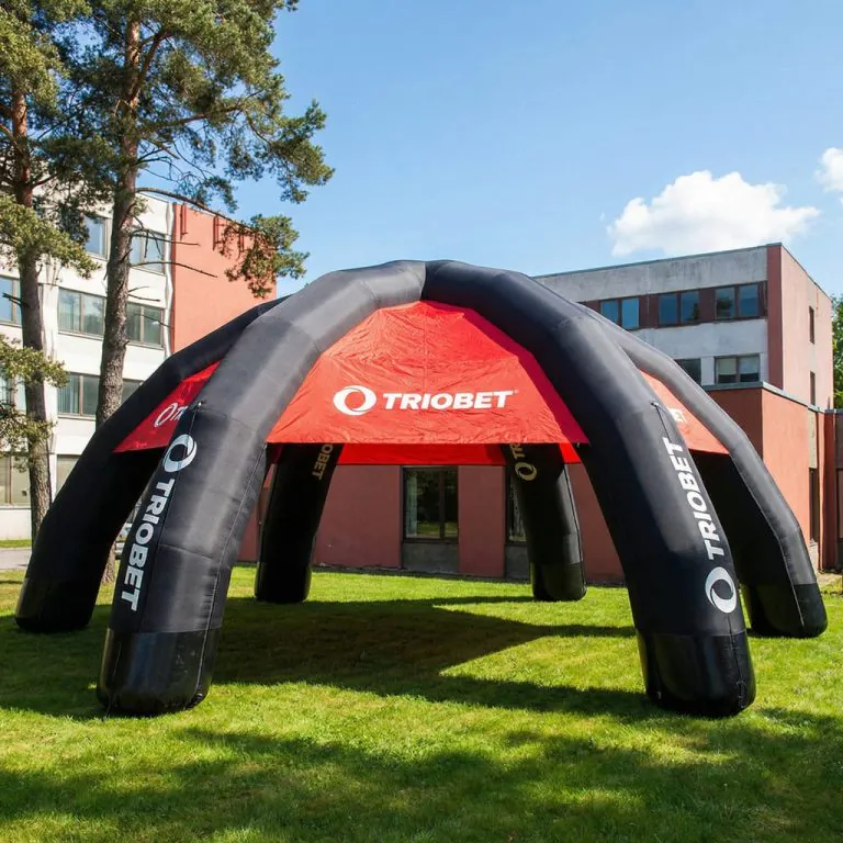 Stort svart och rött uppblåsbart tält på gräsmatta framför moderna byggnader