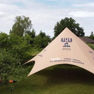 Star tält — beige stjärnformad tält på gräsmatta omgiven av grönska